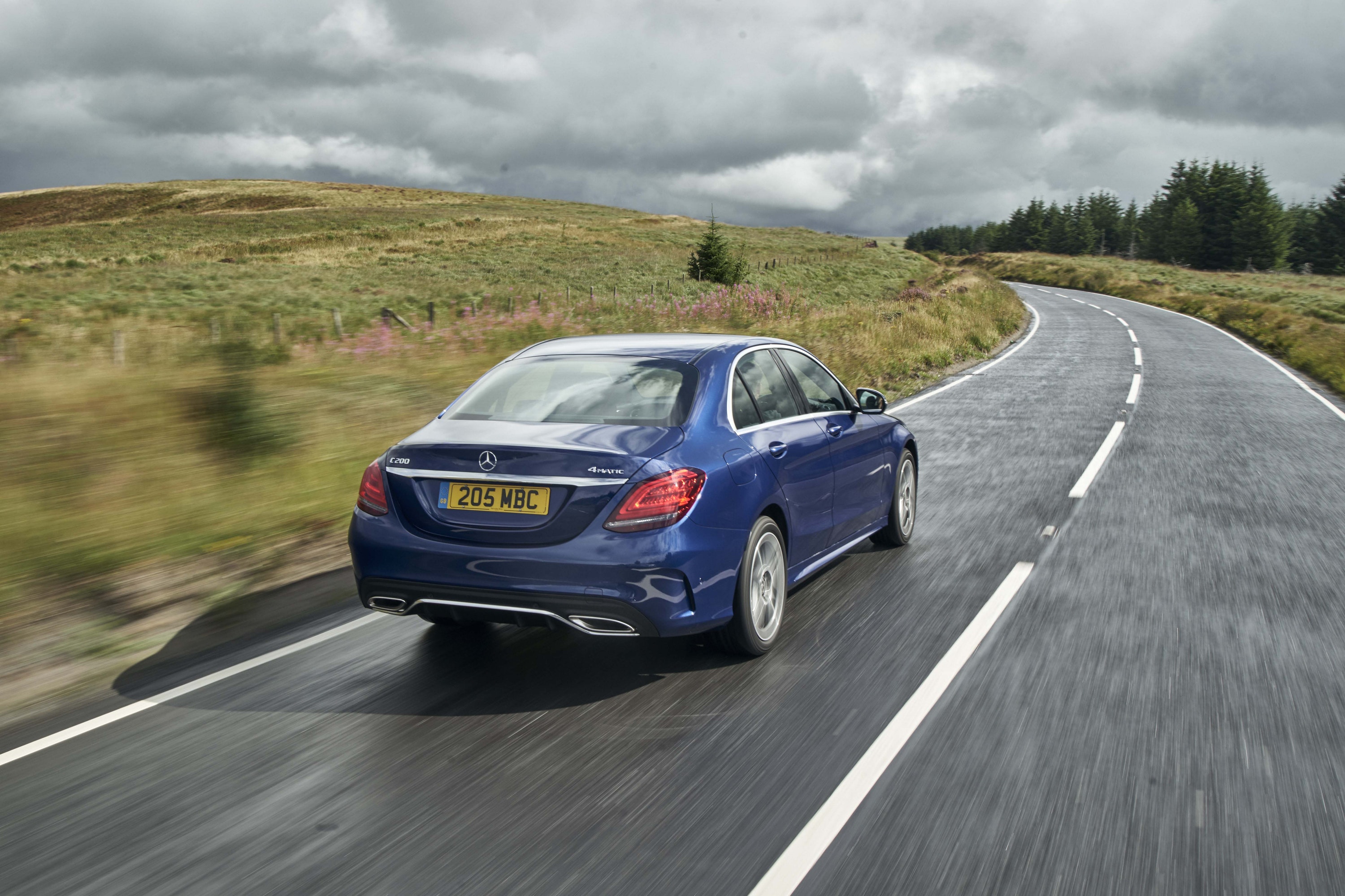 Rear view of blue Mercedes C-Class driving on a road